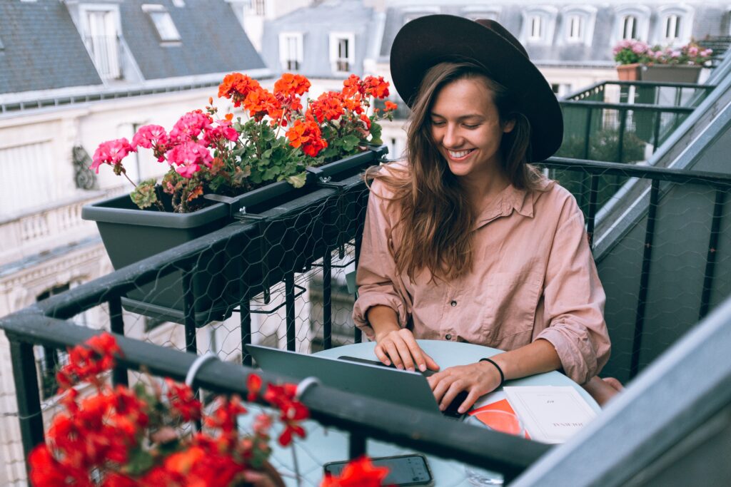 woman smiling and working on the laptop on the balconny
