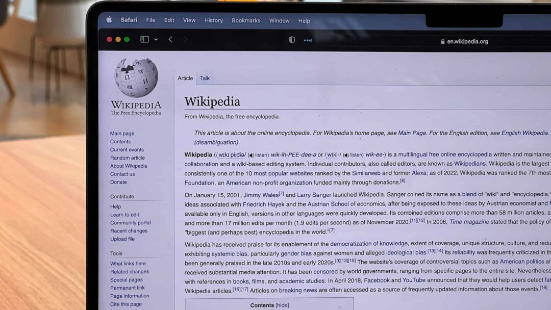 A laptop sits on a table with Wikipedia open
